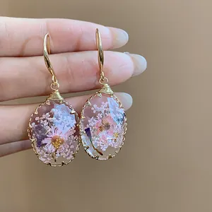 Detailed macro view of resin earrings featuring real dried pink and purple flowers