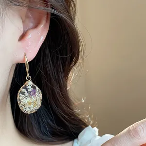 Detailed macro shot of a resin water drop earring with delicate dried floral inserts.