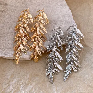 Detailed view of gold and silver leaf feather fringe earrings with metallic textures.