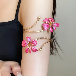 Detailed view of an elegant pink enamel flower arm cuff with gold-tone finish on model