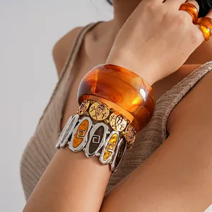 Macro detail of bohemian amber resin bangle and gold cross fish charm bracelet set
