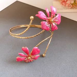 Detail shot of elegant pink enamel flower arm cuff bangle in gold-tone textured metal