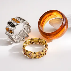 Macro shot of three stylish bracelets including amber bangle and gold fish charm link.