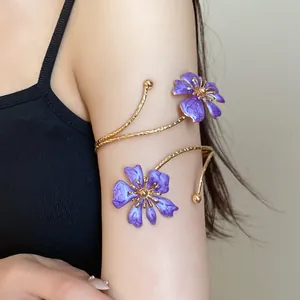 Close-up detail of an elegant gold arm cuff featuring purple enameled flower designs