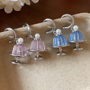 Detailaufnahme von Pudding-Ohrringen mit Perlen und silbernem Kuchenteller-Ständer.