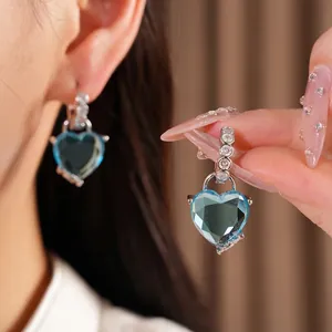 Elegant blue heart earrings with zircon accents, shown worn and held for detail