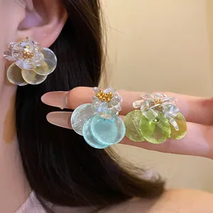 Close-up detail of summer floral earrings with translucent petals and colorful shell discs