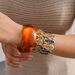 Detail of vintage amber resin bangle and metallic bracelets with fish and cross charms