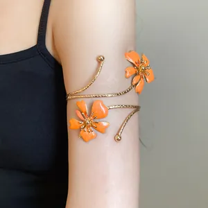 Detail of elegant gold metal arm cuff with orange enamel flowers on upper arm