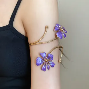 Detail shot of a gold arm cuff featuring elegant purple enamel flowers on an arm