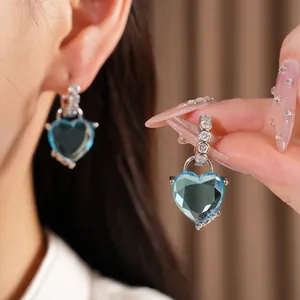 Detailed view of elegant silver hoop earrings with a sparkling blue heart-shaped stone