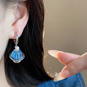 Nahaufnahme eines kreativen blauen Pudding-Ohrrings mit Perlendetail an einem Silberreifen.