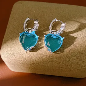 Detailed view of silver hoop earrings featuring blue faceted heart charms with MOM lettering