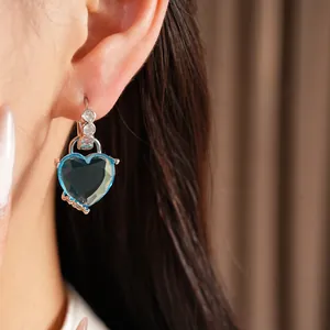 Close-up of elegant blue heart-shaped hoop earring with sparkling cubic zirconia stones.