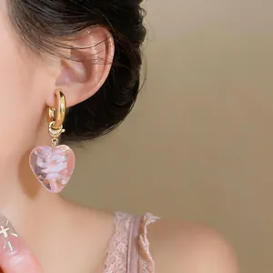 Close-up of a pink heart-shaped glass earring featuring an internal rose pattern