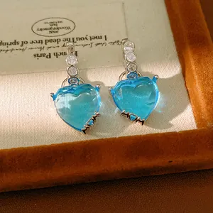 Elegant blue heart-shaped earrings with zircon and MOM text on a velvet jewelry tray.