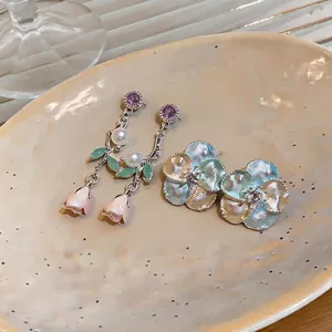 French luxury enamel rose earrings with pearls and floral studs on ceramic plate.