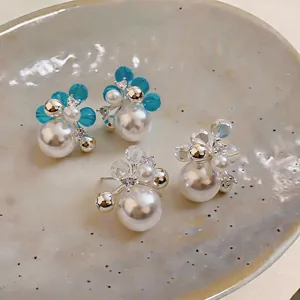 Detailed macro view of French style zircon and pearl stud earrings on ceramic plate