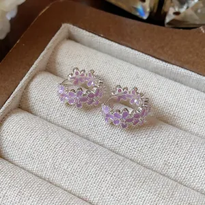 Nahaufnahme von eleganten lila Emaille-Blüten-Ohrringen mit glänzenden Zirkonia-Akzenten.