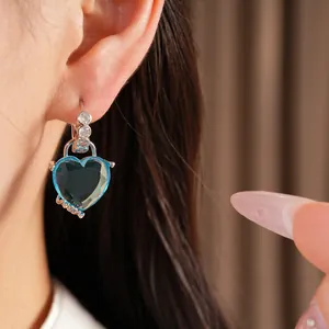 Macro view of silver-tone hoop earring with blue heart-shaped crystal and zircons