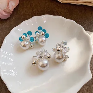 Detailed view of zircon pearl stud earrings with crystal petals on a shell plate