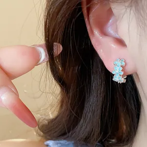 Nahaufnahme eines minimalistischen Creolen-Ohrrings mit hellblauen Blumen und Zirkonia