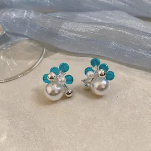 Close-up of elegant French style pearl earrings with blue floral beads and zircon detail