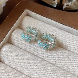 Nahaufnahme von silbernen Creolen mit hellblauen Emaille-Blumen und Zirkonia