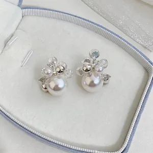 Detailed view of French style pearl and zircon stud earrings in a light blue jewelry box.