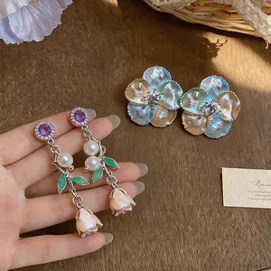 Close-up detail of luxury French enamel rose earrings featuring elegant pearl accents