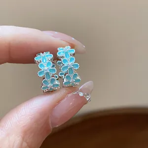 Nahaufnahme kleiner blauer Emaille-Blumenohrringe mit funkelnden Zirkonia-Verzierungen