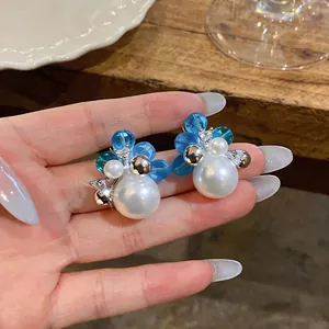 Close-up detail of elegant French style pearl earrings with blue beads and sparkling zircons