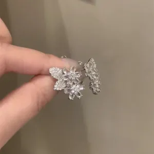 Primo piano dettagliato di squisiti orecchini a lobo a fiore in argento con zirconi.