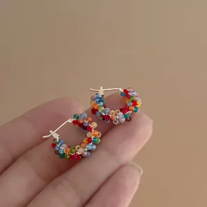 Dettaglio di orecchini a cerchio colorati con perline arcobaleno per un look estivo