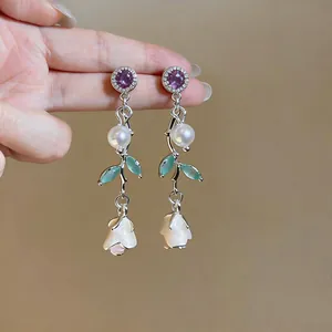 Close-up of French style drip glaze rose flower drop earrings with purple gemstone