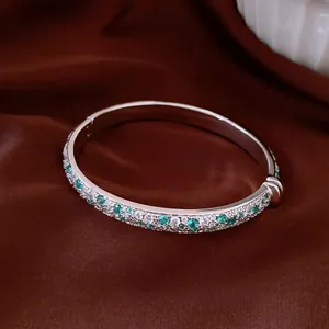 Detailed close-up of a silver bangle inlaid with mint green and clear zircon stones.