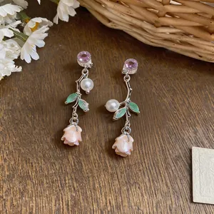 Detailed view of French luxury rose earrings with pearls and enamel leaves.