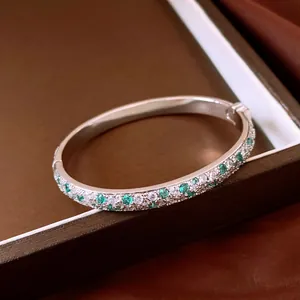 Close-up of elegant silver bangle with sparkling mint green and white zircon stones