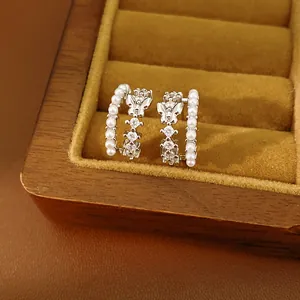 Close-up of elegant double-layered butterfly earrings with pearls and zirconia