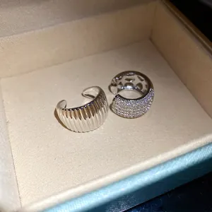 Macro detail of zircon-encrusted and ribbed silver metal ear cuffs in a jewelry gift box