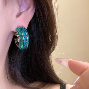 Dettaglio di orecchini a cerchio a C vintage con zirconi verdi e blu scintillanti