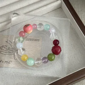 Close-up detail of the colorful resin fruit bead bracelet with apple charm on stand