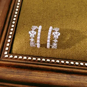 Detailed close-up of double-layer C-shaped earrings with pearl and zircon butterfly