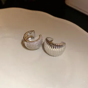 Detail view of silver ear cuffs with cubic zirconia and ribbed texture on ceramic tray