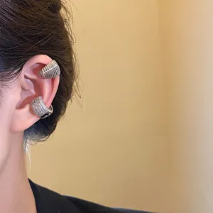 Detailed view of silver-toned ear cuffs with micro-paved zircons and ribbed metal design