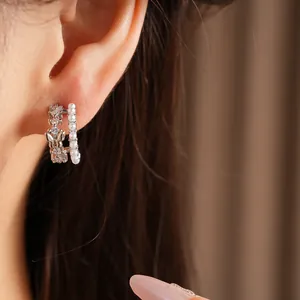 Detail of double-layer C-shaped earring with pearls and butterfly zirconia on ear