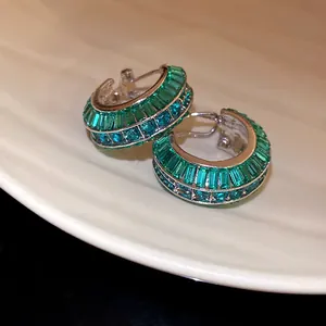 Dettaglio ravvicinato di orecchini a cerchio a C con zirconi verde smeraldo e tondi