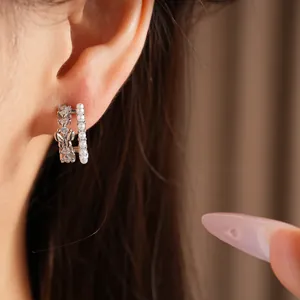 Close-up of elegant double-layer butterfly earrings with pearls and zircons on ear.