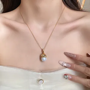 Detail view of 14k gold plated acorn necklace with pearl and zircon on model.