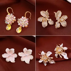 Four styles of elegant floral zircon earrings shown on a dark brown fabric background.